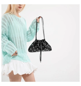 Detail of black glossy drawstring bucket bag with silver studs and metal buckle finish