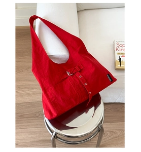 Détail du sac fourre-tout en toile rouge avec boucle métallique et étiquette de logo