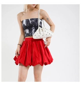 White leather bucket bag with metallic rivets and drawstring closure on a fashion model