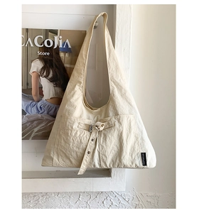 Détail du sac à épaule en toile beige avec grandes poches avant et sangles à boucle métal