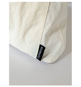 Gros plan d'un sac cabas en toile beige avec texture plissée et étiquette tissée OUPINFAN