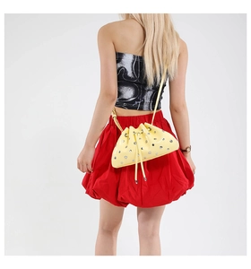Detail of yellow patent leather dumpling bag featuring silver metal eyelets and drawstring closure