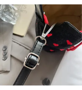 Detail of silver metal buckle and red drawstring on a black velvet heart bucket bag
