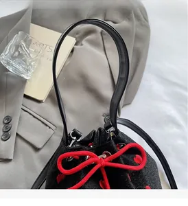 Detail of black canvas bucket bag featuring red heart embroidery and rope drawstring bow