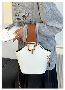 Dettaglio della borsa a secchiello in pelle bianca con fibbia dorata e tracolla marrone