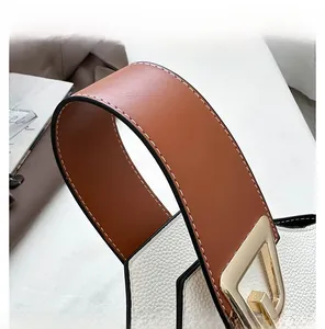 Dettaglio borsa in pelle bianca con manici marroni e fibbia in metallo dorato