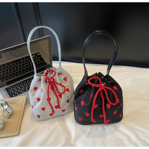 Detail of silver and black bucket bags with red heart embroidery and drawstring closure