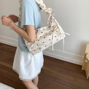 Floral fabric shoulder bag with red bows and scrunchie strap on model in cozy room