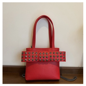 Macro detail of red lychee grain leather handbag featuring metallic stud decorations