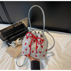Detail of silver glitter bucket bag with red hearts, drawstring closure and crossbody strap