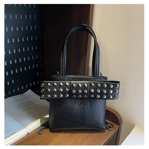 Detail of black pebbled leather bag with rivet-studded bow and silver chain strap