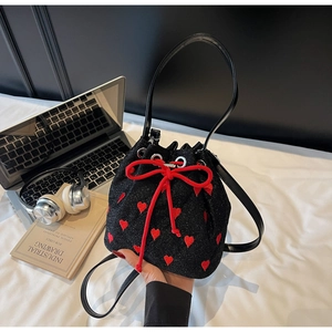 Detail shot of black sequin bucket bag with red hearts and drawstrings on desk