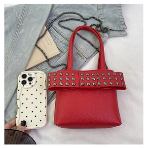 Macro view of bright red leather mini bag with rivet bow detail and silver chain strap