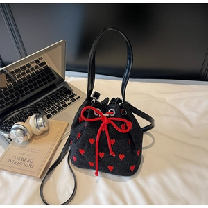 Close-up of black bucket bag with red heart embroidery and drawstring bow detail