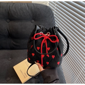 Close-up of black drawstring bucket bag with red heart embroidery and glitter texture