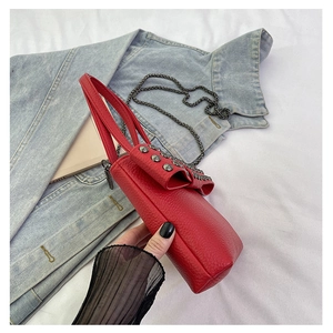 Macro shot of red leather phone bag with punk style metal rivets and bow detail
