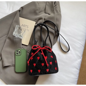 Detail of black velvet bucket bag with red heart embroidery and drawstring closure