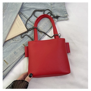 Detail of red lychee textured leather mini square bag with metal chain on denim jacket