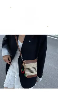 Straw bucket bag detail featuring hand-woven beige fibers and cherry charm pendant
