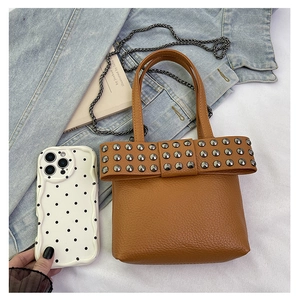 Detailed view of punk style mini bag with rivet bow and chain on denim jacket