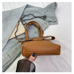 Macro view of the thick bottom base and leather texture of the brown rivet crossbody bag