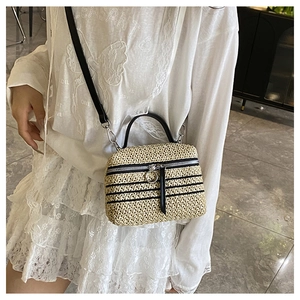Détail du sac en paille beige tissé main avec rayures noires et poignées en cuir