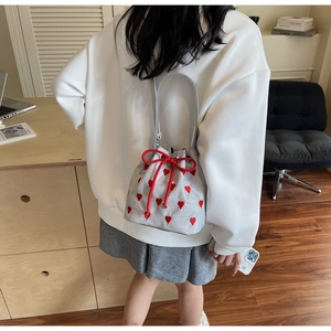 Close-up of drawstring bucket bag with red heart embroidery and silver leather handle