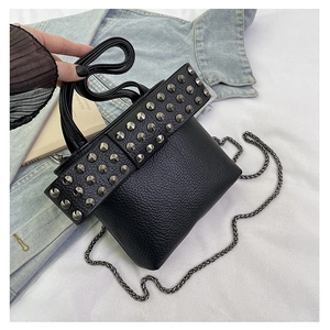 Detail of black pebbled leather crossbody bag with silver cone studs and metal chain strap