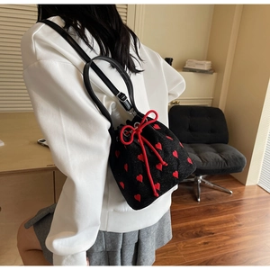 Detail of black drawstring bucket bag with red heart embroidery and bow closure