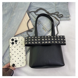 Detail of mini black pebbled leather crossbody bag with rivet bow and chain strap