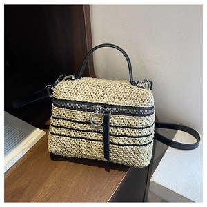 Détail du sac bandoulière en paille tissée avec garniture en cuir noir et fermetures éclair