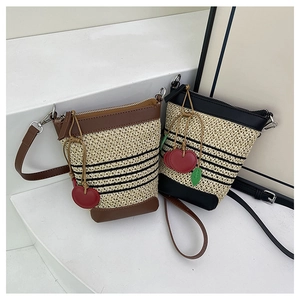Detail of woven raffia bags with leather trim and decorative cherry charms