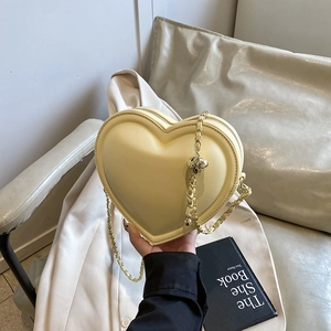 Chic cream heart-shaped crossbody bag with gold chain strap and metal ball detail