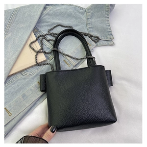 Detail of black pebbled leather mini bucket bag with metal chain strap and denim accents