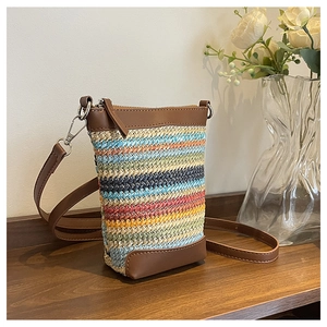 Gros plan d'un mini sac en paille tissée à rayures colorées et finitions en cuir brun