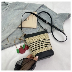 Detailed macro view of woven raffia texture with black leather trim and cherry charm