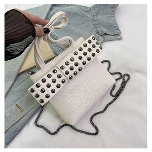 Detail of white lychee leather mini bag with rivet bow decoration and chain strap