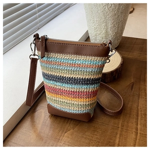 Détail du sac bandoulière en paille rayé coloré avec bordure en cuir marron et fermeture
