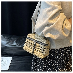 Détail du sac bandoulière en paille beige tissée avec rayures noires et anneau zippé