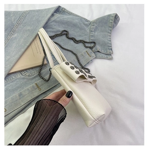 Detail of white lychee leather mini crossbody bag with metal rivets and chain strap