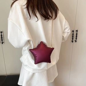 Sac bandoulière bordeaux en forme d'étoile avec chaîne dorée sur une tenue blanche