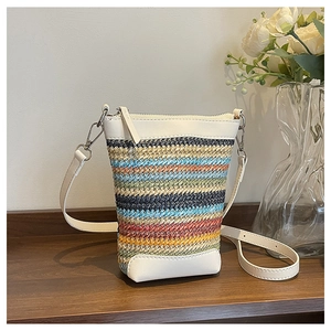 Close-up of bohemian colorful woven crossbody bag with white leather trim and silver metal hook