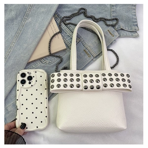 Close-up of white leather bow bag with rivets on denim jacket with a phone case