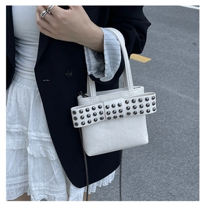 Detail of cream leather handbag with studded bow and metallic chain strap in street style