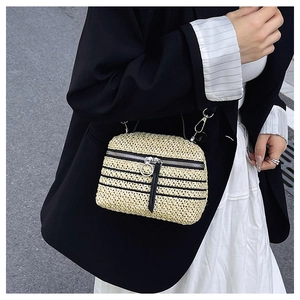 Détail du sac bandoulière en paille tissée avec rayures noires et fermeture éclair argentée