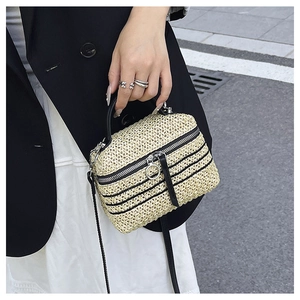 Détail du sac bandoulière en paille tissé main avec rayures noires et zip à anneau argenté