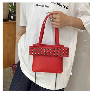 Detail of red leather handbag featuring large bow design and silver metal rivets