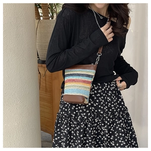 Détail d'un sac seau tissé à rayures colorées avec garniture en cuir et bandoulière