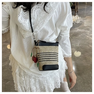Straw woven crossbody bucket bag with black leather trim and cherry charm detail