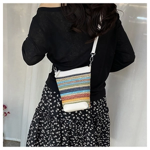 Detail of colorful woven straw crossbody bag with white leather trim and metal hardware